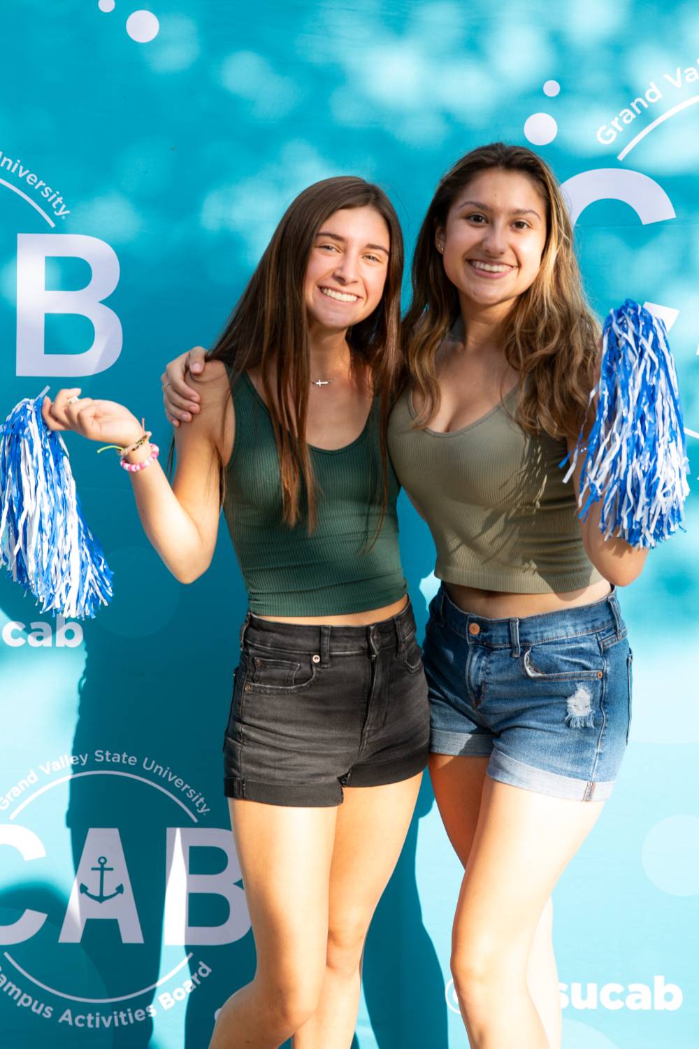 two students posing in front of CAB backdrop at Laker Kickoff photo booth smiling